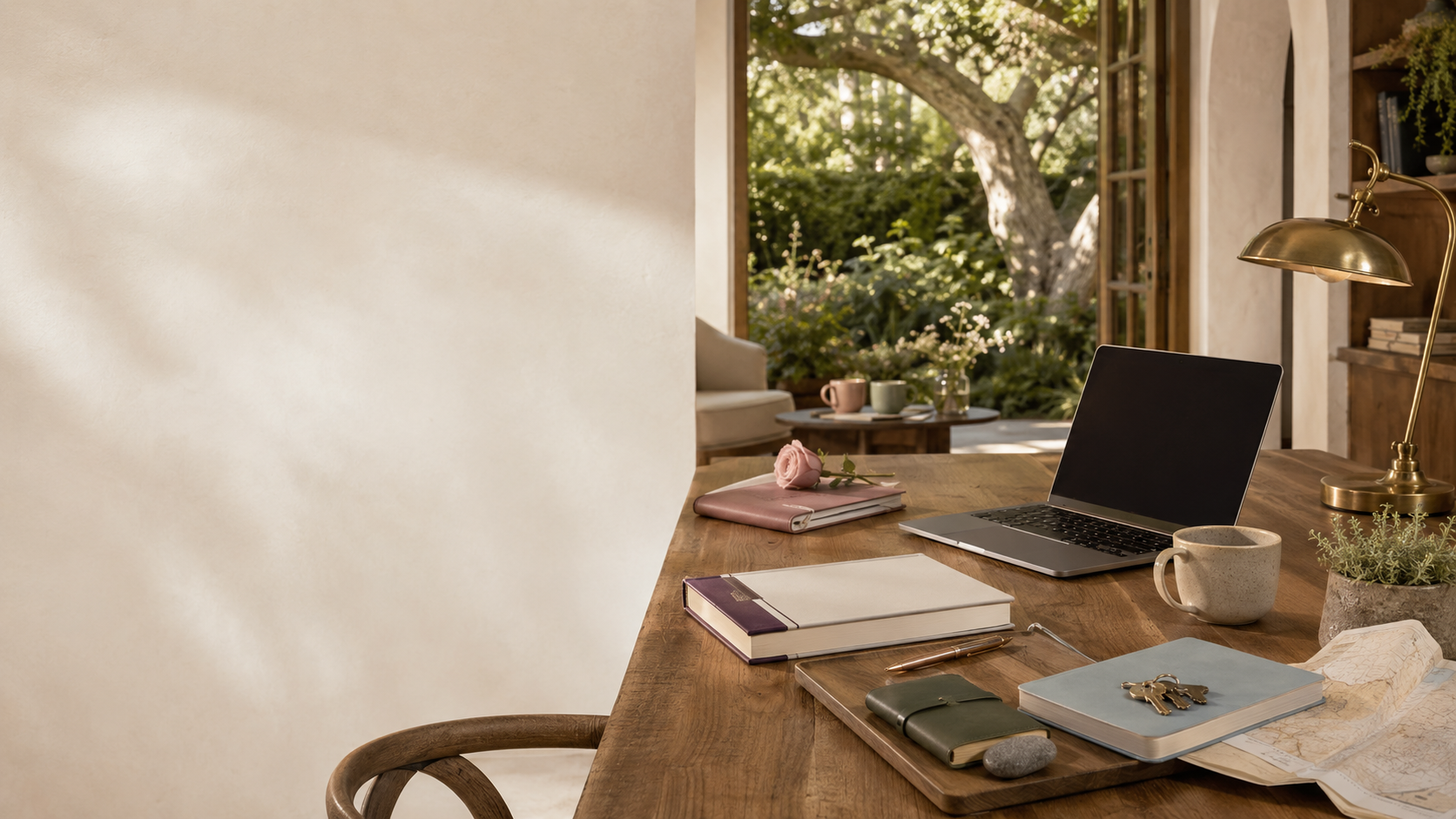 A warm Best Collective studio table with a laptop, notebooks, planning tools, and sunlight from a garden doorway